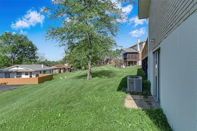 view of green lawn with central AC unit and a residential view