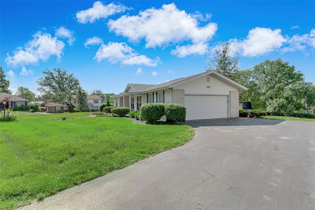 view of front of home with asphalt driveway, a garage, a front yard, and brick siding