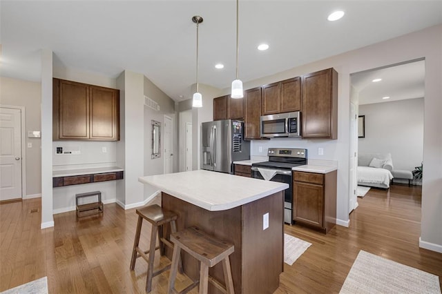 1051 Timber Creek Ln, Imperial, MO 63052 - kitchen featuring appliances with stainless steel finishes, wood finished floors, light countertops, a breakfast bar, and recessed lighting