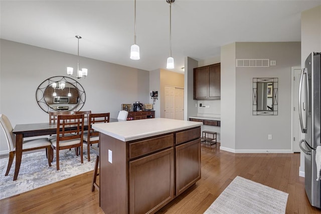 1051 Timber Creek Ln, Imperial, MO 63052 - kitchen featuring stainless steel appliances, wood finished floors, light countertops, a kitchen island, and decorative light fixtures