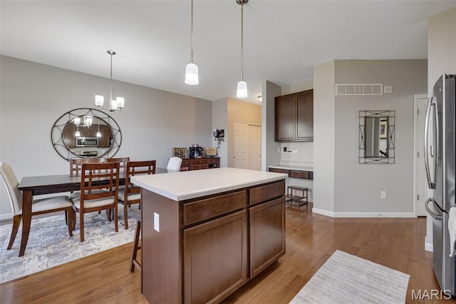 1051 Timber Creek Ln, Imperial, MO 63052 - kitchen with appliances with stainless steel finishes, wood finished floors, light countertops, a kitchen island, and pendant lighting