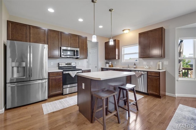 1051 Timber Creek Ln, Imperial, MO 63052 - kitchen with appliances with stainless steel finishes, a center island, dark brown cabinets, light wood-style floors, and recessed lighting
