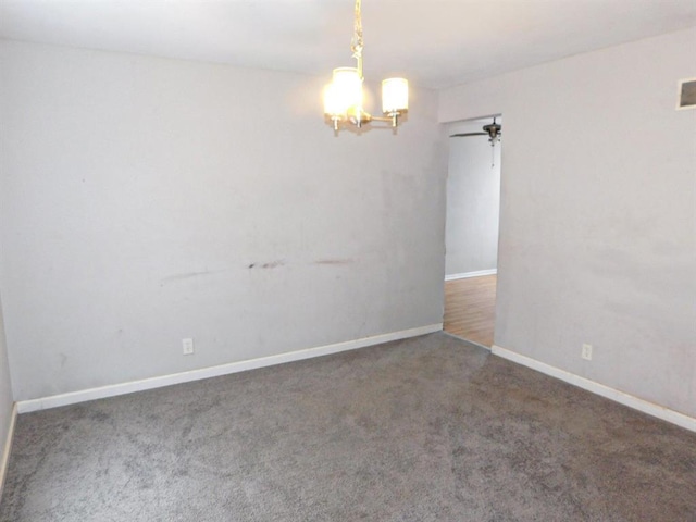 spare room featuring a chandelier, carpet floors, and baseboards