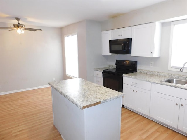 kitchen with black appliances, a sink, plenty of natural light, and light wood-style floors