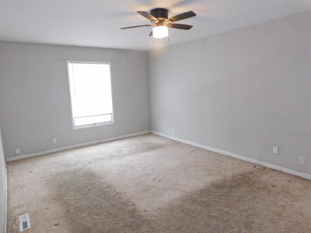 carpeted empty room with ceiling fan and baseboards