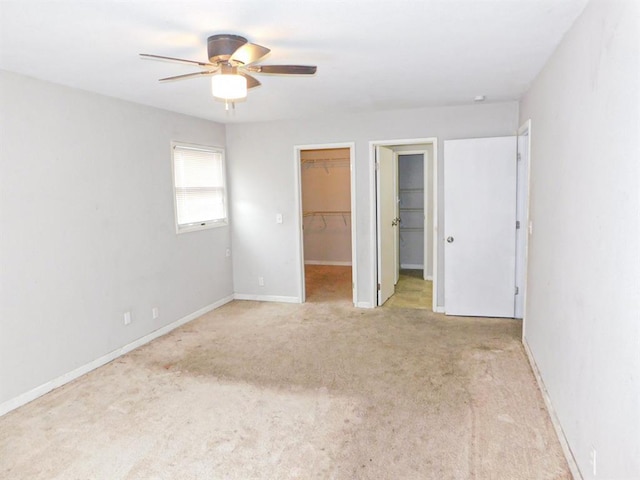 unfurnished bedroom featuring carpet flooring, a spacious closet, ceiling fan, and baseboards