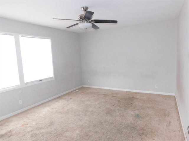 empty room with carpet floors, a ceiling fan, and baseboards