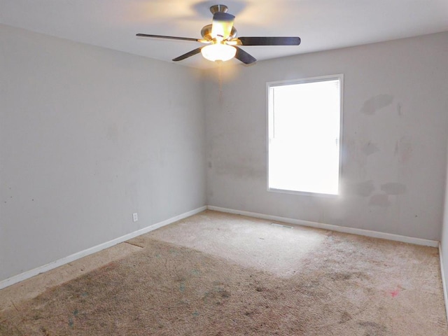 carpeted spare room with ceiling fan and baseboards