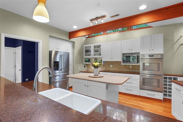 19072 Bear Trail Rd, Glencoe, MO 63038 - kitchen with appliances with stainless steel finishes, a sink, white cabinetry, decorative backsplash, and glass insert cabinets