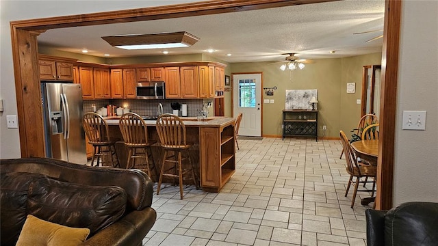 189 County Road 657, Cape Girardeau, MO 63701 - kitchen with appliances with stainless steel finishes, backsplash, a breakfast bar, a ceiling fan, and open shelves