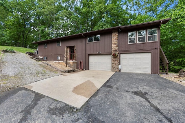view of front facade featuring asphalt driveway, stone siding, and an attached garage