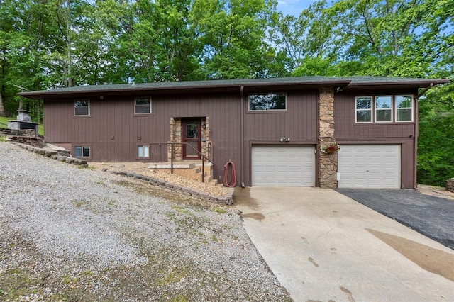 view of front facade with asphalt driveway, an attached garage, and stone siding
