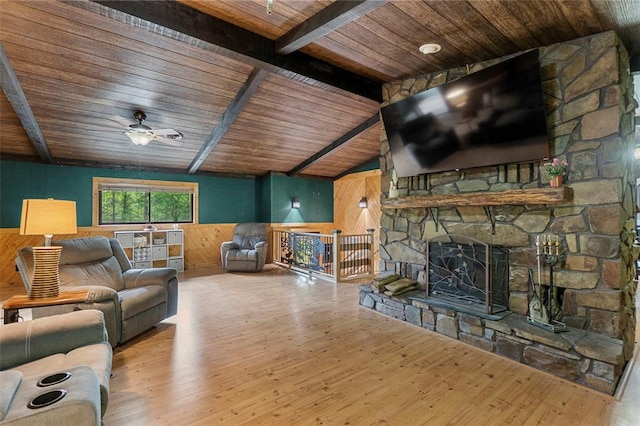 living room featuring wooden walls, wood ceiling, wood finished floors, a wainscoted wall, and a ceiling fan