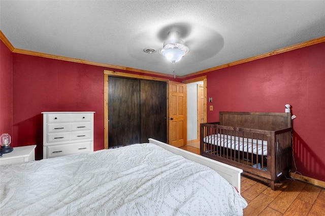 bedroom featuring hardwood / wood-style flooring, ornamental molding, a closet, baseboards, and a textured ceiling
