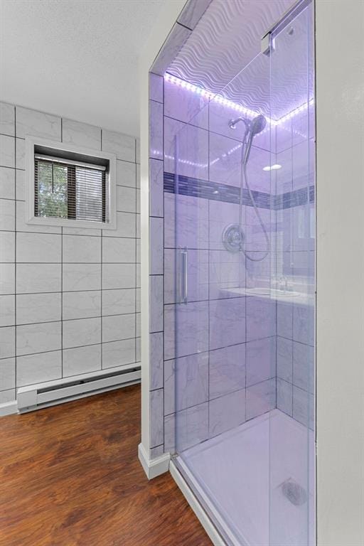 bathroom with a baseboard heating unit, a shower stall, and wood finished floors