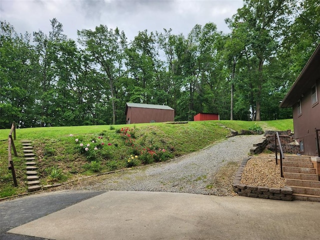 view of grassy yard featuring stairs, a storage unit, and an outdoor structure