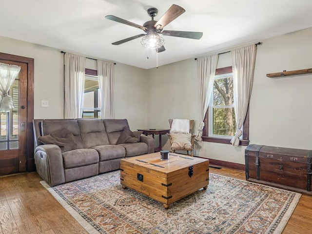 living area featuring wood finished floors, ceiling fan, and baseboards