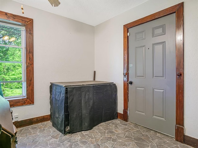 bedroom featuring baseboards, multiple windows, stone finish flooring, and a textured ceiling