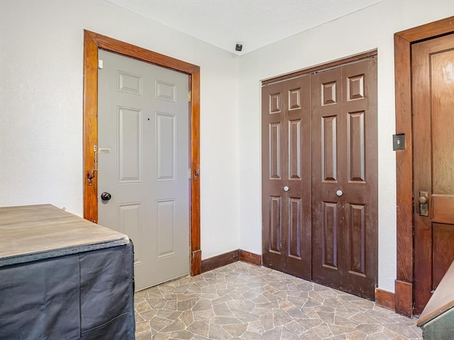 foyer entrance with baseboards and stone flooring