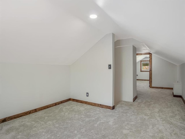 bonus room with light colored carpet, lofted ceiling, and baseboards