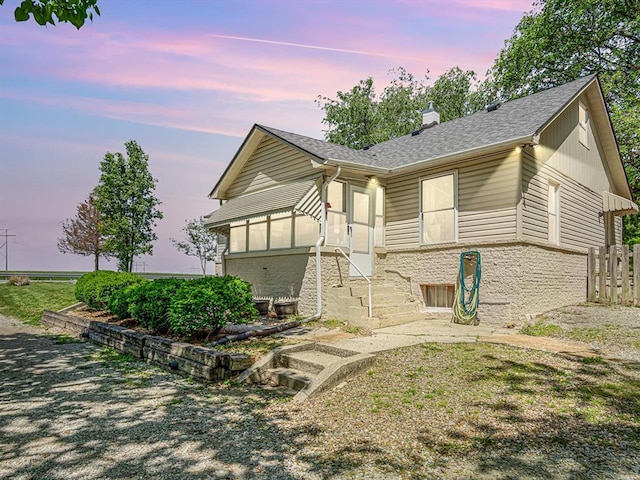 ranch-style home featuring roof with shingles, a chimney, stone siding, and fence