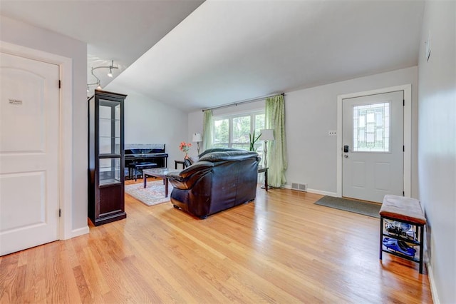 living room featuring light wood-style floors, healthy amount of natural light, lofted ceiling, and baseboards