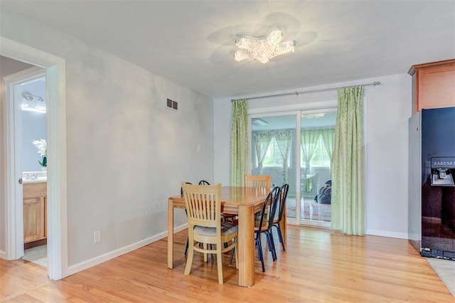 dining area with a chandelier, light wood-style flooring, and baseboards