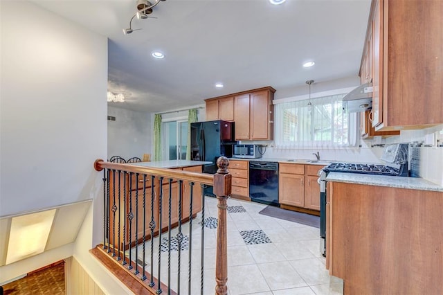 kitchen with appliances with stainless steel finishes, exhaust hood, light countertops, light tile patterned floors, and a sink