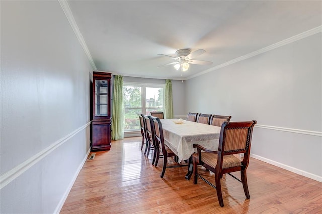 dining room featuring ornamental molding, ceiling fan, light wood finished floors, and baseboards