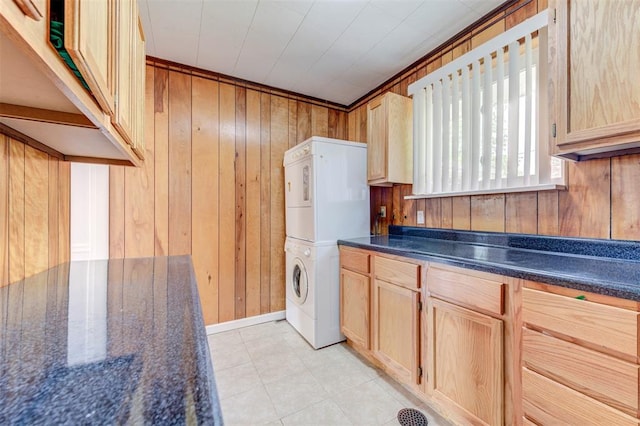 clothes washing area with stacked washing machine and dryer, wood walls, and cabinet space