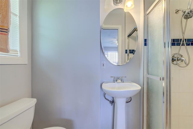 full bathroom featuring tiled shower and toilet