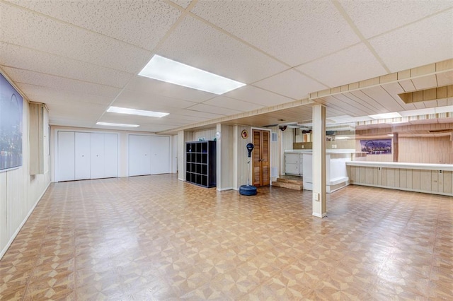 finished basement with a paneled ceiling and baseboards
