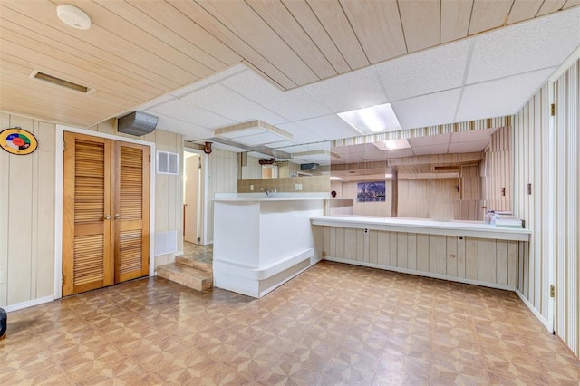kitchen with wooden walls, baseboards, parquet flooring, and a paneled ceiling