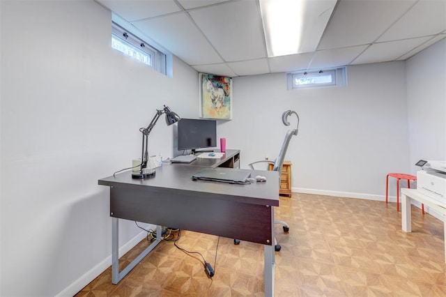 home office featuring healthy amount of natural light, a drop ceiling, and baseboards