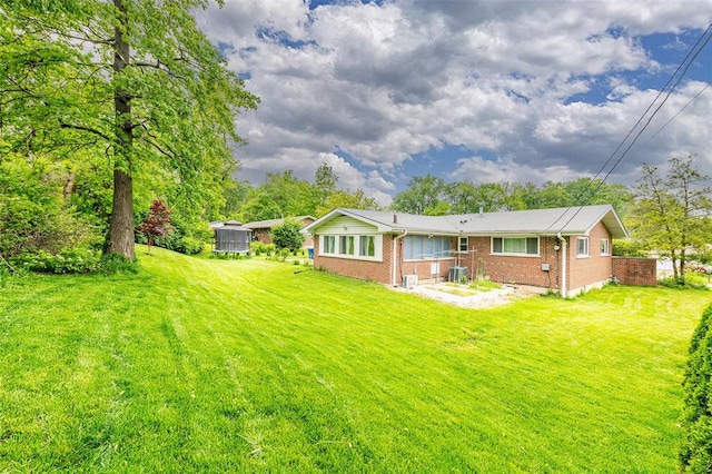 back of house featuring brick siding and a lawn