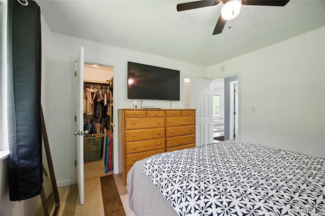 8544 Lake Dr, Cedar Hill, MO 63016 - bedroom with a walk in closet, wood finished floors, a closet, a ceiling fan, and a textured ceiling
