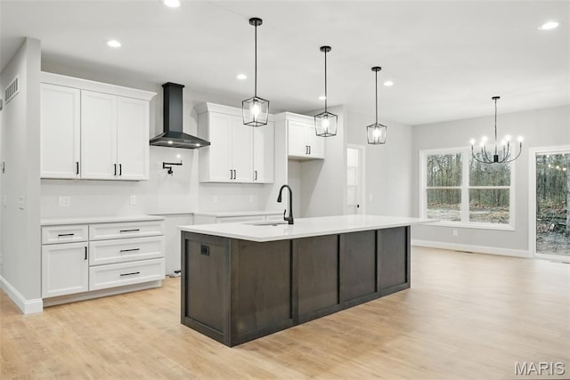 31998 Fairway Dr N, Foristell, MO 63348 - kitchen with wall chimney range hood, light wood finished floors, white cabinetry, recessed lighting, and an island with sink