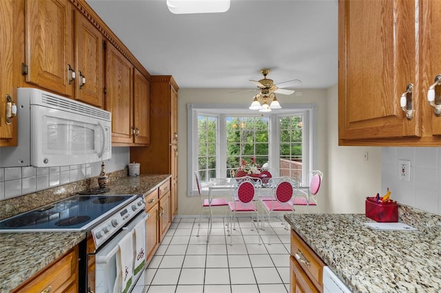 308 Wildbrier Dr, Ballwin, MO 63011 - kitchen with white microwave, range with electric cooktop, backsplash, brown cabinetry, and ceiling fan