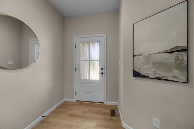 doorway to outside with light wood finished floors and baseboards