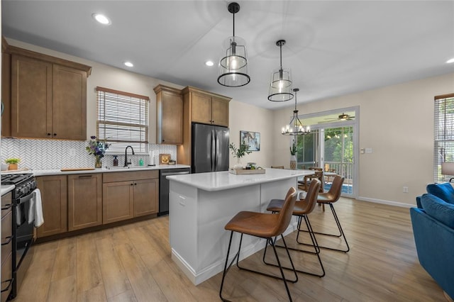 kitchen featuring freestanding refrigerator, dishwashing machine, gas stove, a sink, and light wood finished floors