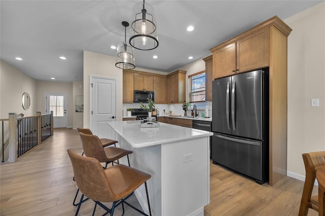 kitchen with appliances with stainless steel finishes, a kitchen island, plenty of natural light, a sink, and recessed lighting