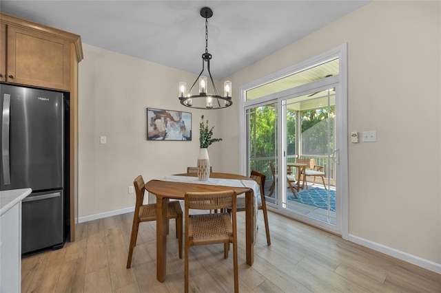 dining space featuring a chandelier, light wood-type flooring, and baseboards