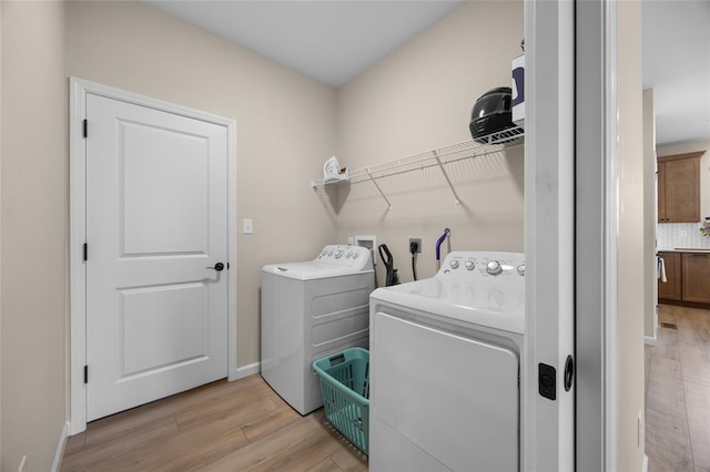 washroom featuring washing machine and clothes dryer, light wood-type flooring, and baseboards