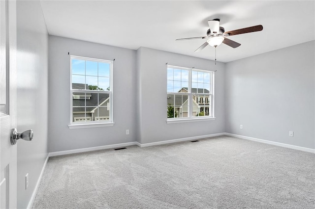 carpeted empty room with plenty of natural light, ceiling fan, and baseboards