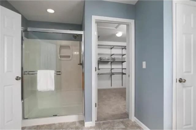 full bathroom featuring a shower stall, baseboards, and a closet