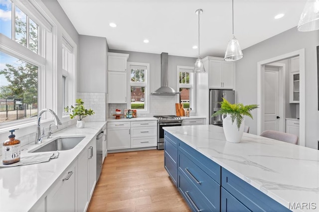 6602 Alamo Ave, Clayton, MO 63105 - kitchen featuring wall chimney range hood, appliances with stainless steel finishes, blue cabinets, plenty of natural light, and recessed lighting