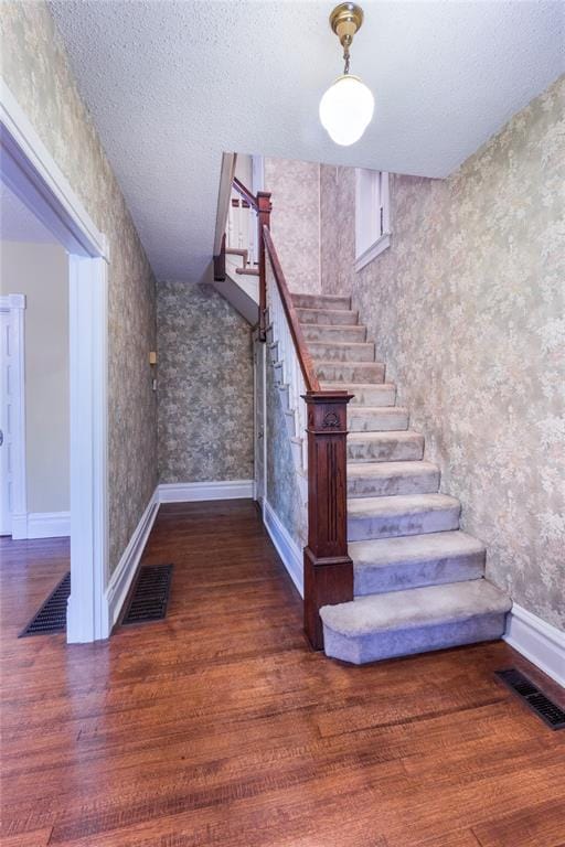4526 Gibson Ave, Saint Louis, MO 63110 - stairway featuring wallpapered walls, wood finished floors, baseboards, and a textured ceiling