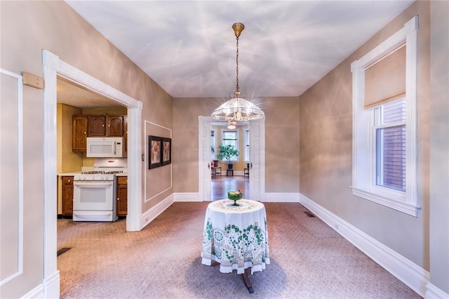 4526 Gibson Ave, Saint Louis, MO 63110 - dining space featuring light colored carpet, a chandelier, and baseboards