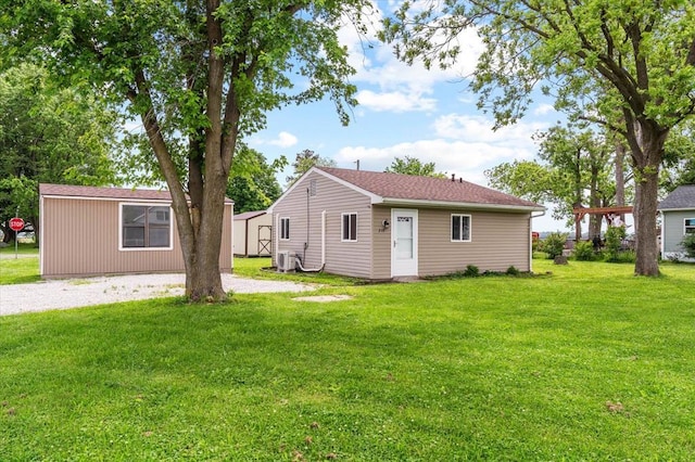 back of house featuring a yard, central AC unit, an outdoor structure, and driveway