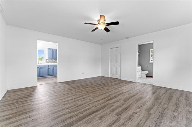 unfurnished living room with a ceiling fan, wood finished floors, plenty of natural light, and baseboards
